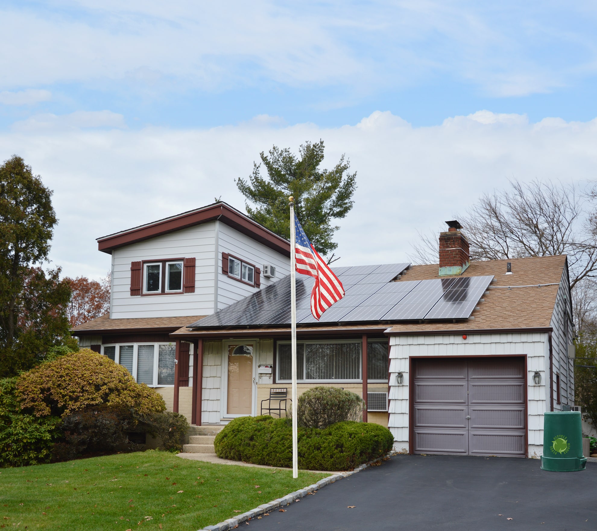 american flag pole suburban ranch style home with solar panel on roof
