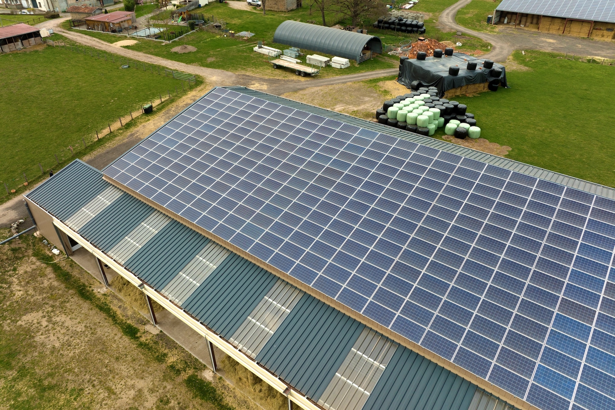 aerial view of farm building with photovoltaic solar panels mounted on rooftop for producing clean ecological electricity.